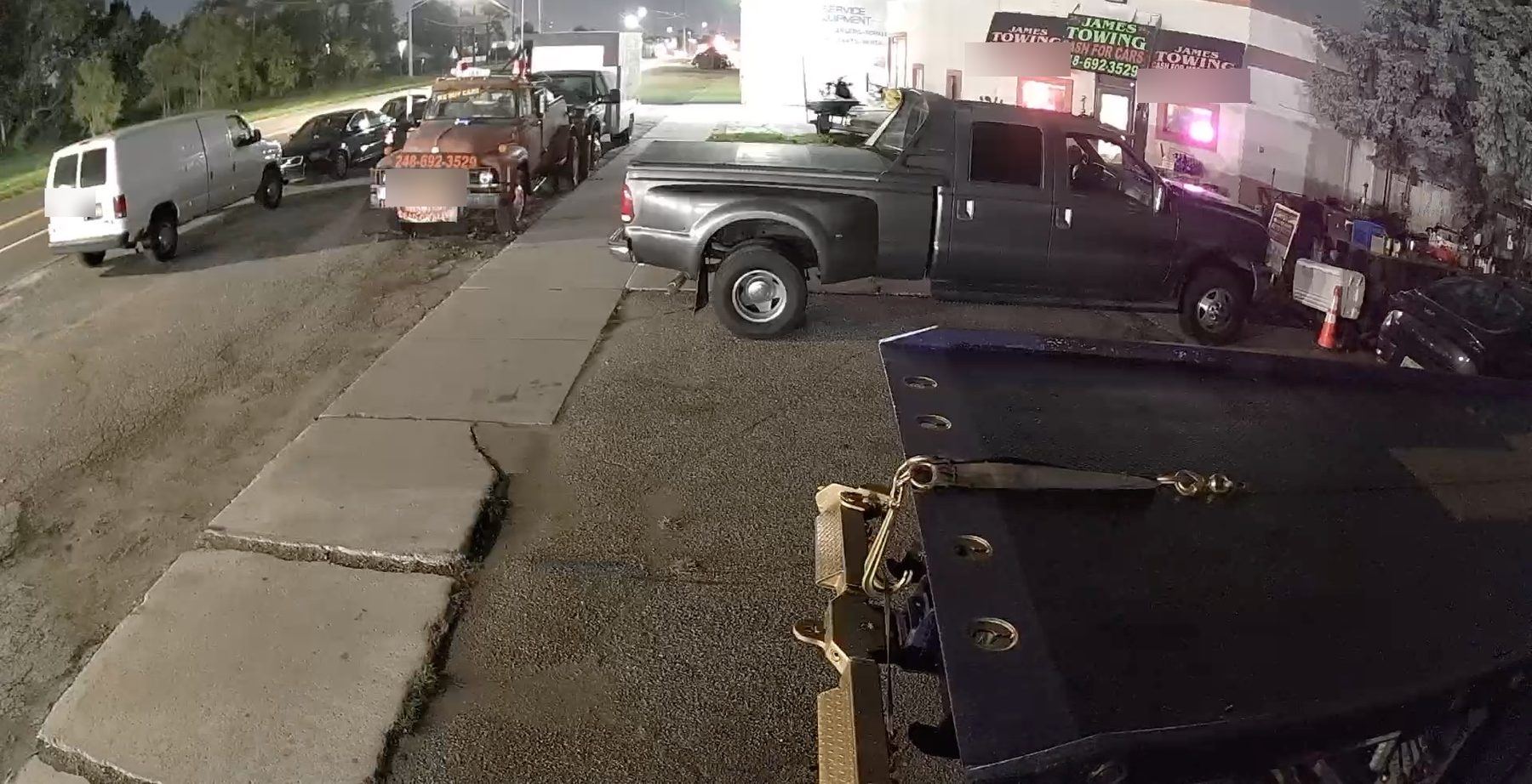 James Towing yard on Dequindre Rd at night with trucks and the flatbed bed